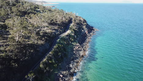 drone pan following cars driving down stunning road near coast with trees and blue ocean in tasmania australia