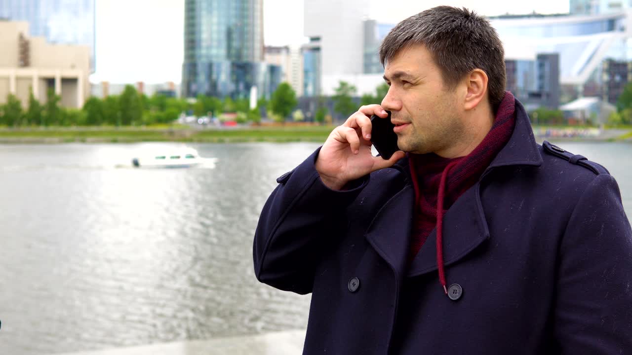 한 남자가 도시 풍경을 배경으로 드폰으로 이야기하고 있습니다.