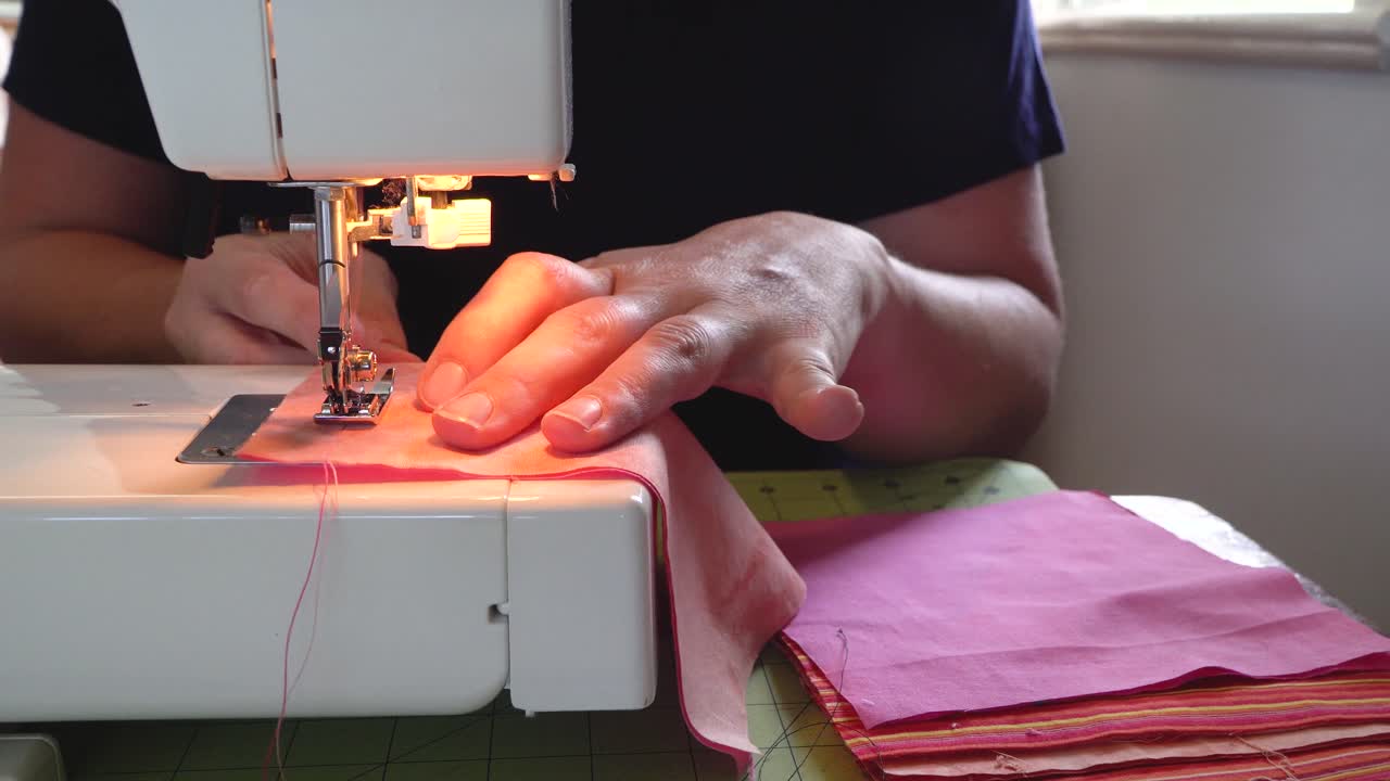 vista de cerca de las manos de la mujer cosiendo cuadrados de tela en la máquina de coser