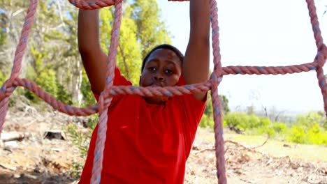 Niño-Decidido-Trepando-Una-Red-Durante-La-Carrera-De-Obstáculos