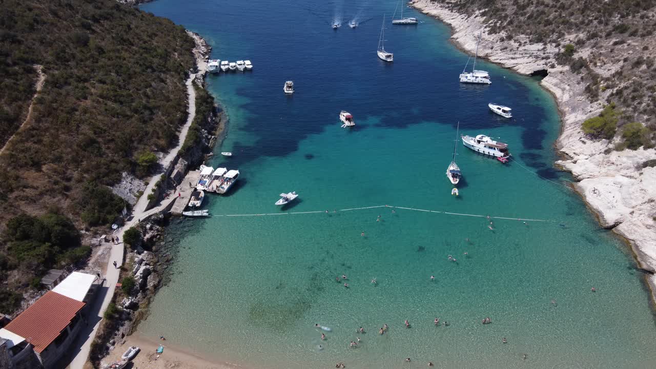 Aerial view of Boats and Yachts at Porat Bay of Bisevo island, Croatia with nautical tourists swimming in turquoise clear water inlet
