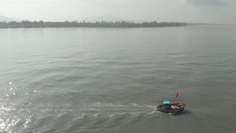 high-profile-follow-Drone-shot-of-small-colourful-Indian-fishing-boat-going-out-to-sea-looking-towards-shore