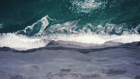 Drohnenaufnahme,-Die-Seitwärts-Fliegt,-Wobei-Die-Kamera-Nach-Unten-Geneigt-Ist,-über-Dem-Grünen-Meer-Und-Dem-Schwarzen-Strand-In-Island-4k