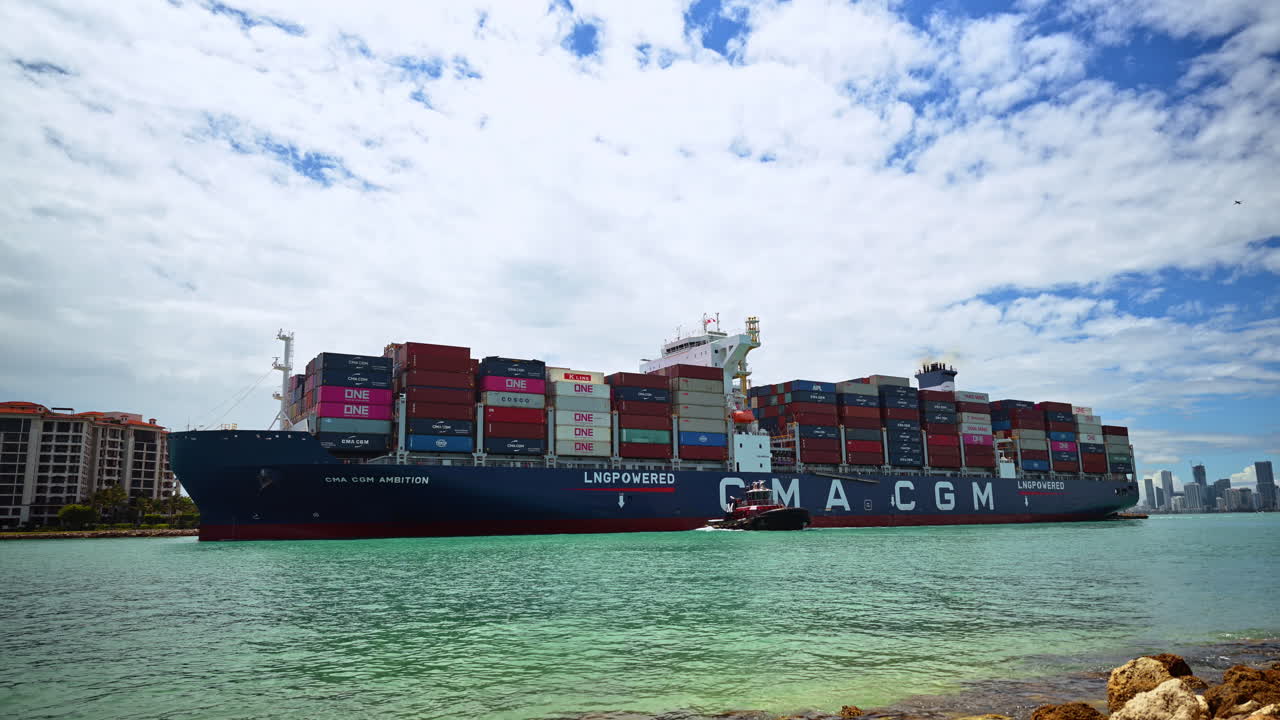 Miami, USA, 9. april 2026: Containerskib sejler gennem Government Cut i Miami. Perspektiv af et stort fragtskib i turkisblåt vand nær beboelsesbygninger i Miami Beach.