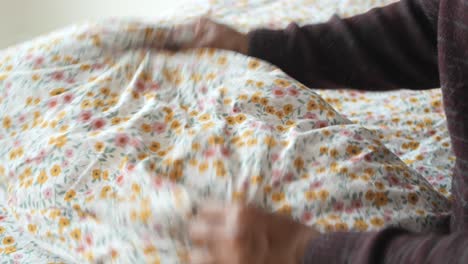 person making a bed with floral sheets