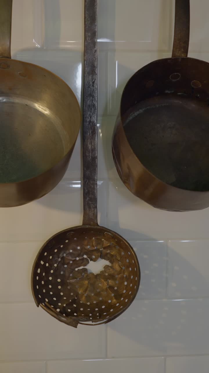 Vintage Copper Kitchen Utensils Hanging on a Tiled Wall