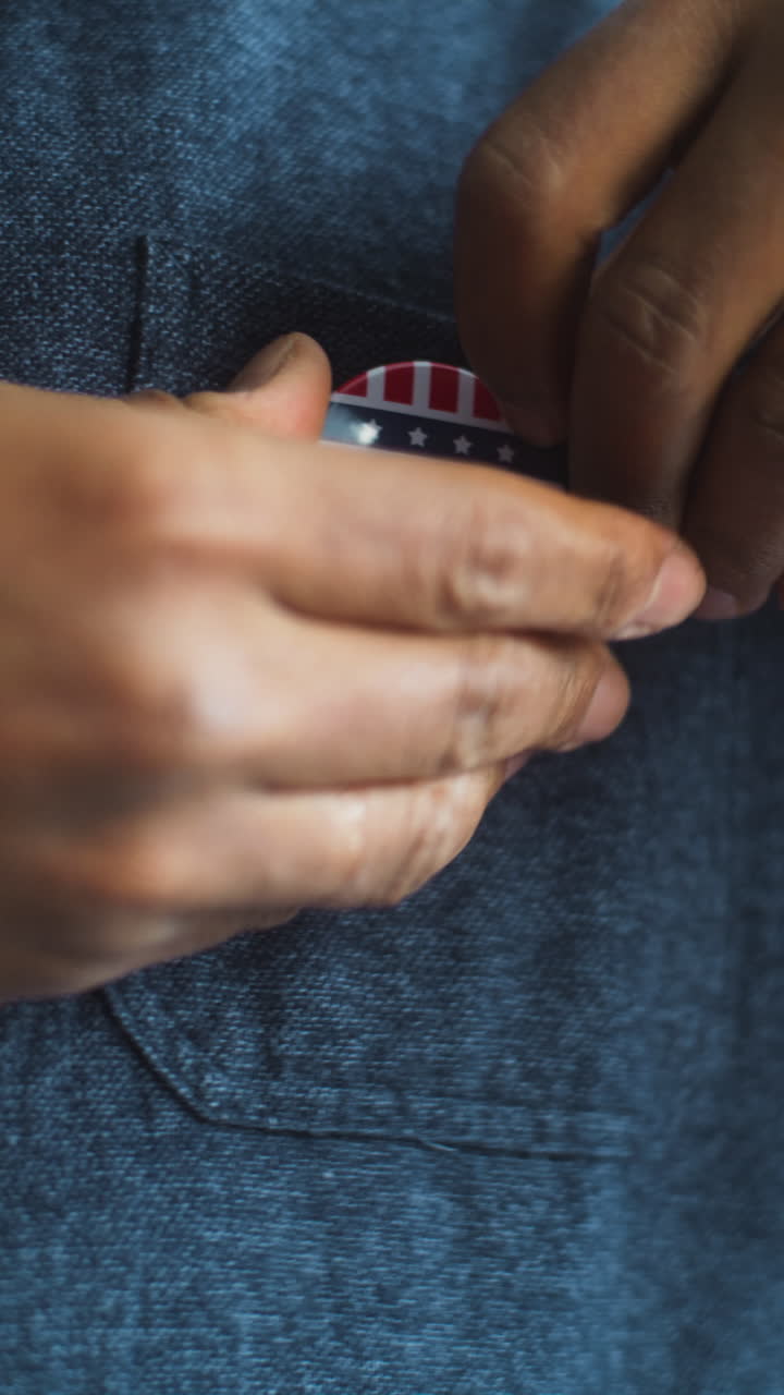 African American us Citizen Puts on Badge with Usa Flag Logo Close up of Anonymous African American Man or us Citizen Putting on Badge with Usa Flag Logo and Inscription i Voted Male Voter at Polling Station after Voting Election Day in the United States