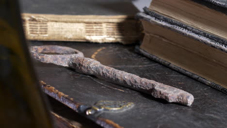 primer plano que revela la cacerola de la vieja llave oxidada por los libros sobre la mesa de madera