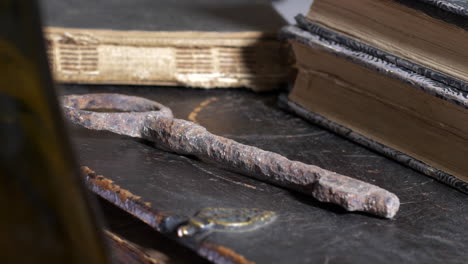 close-up revealing pan of old rusty key by books on wooden table