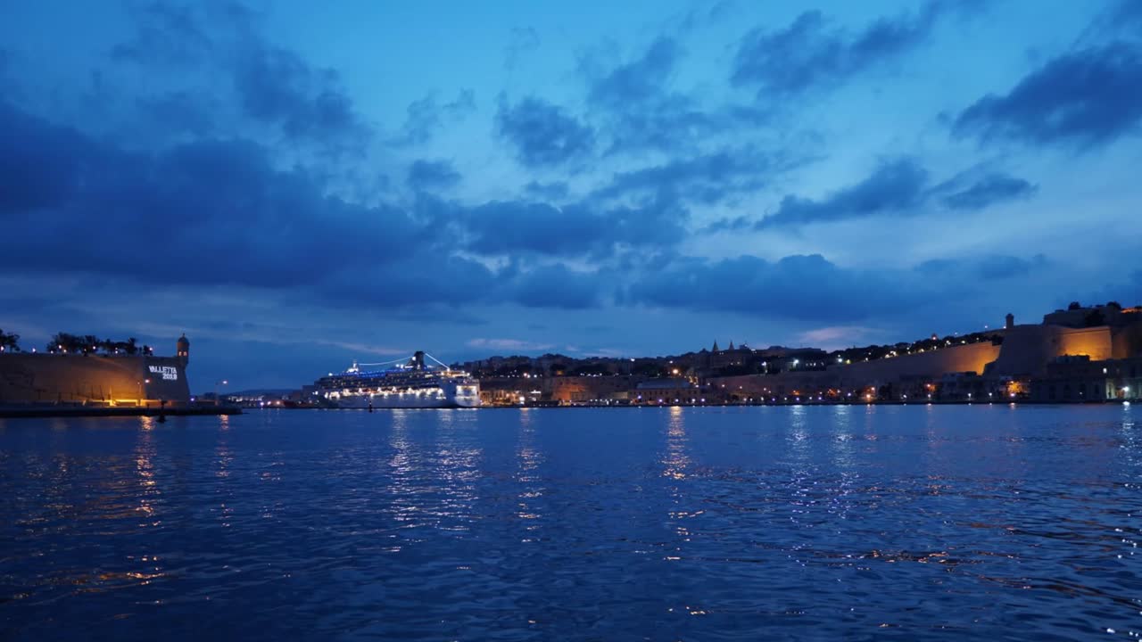 Zeitraffer Malta von Birgu nach Valletta bei Sonnenuntergang, Nacht, abfahrendes Kreuzfahrtschiff