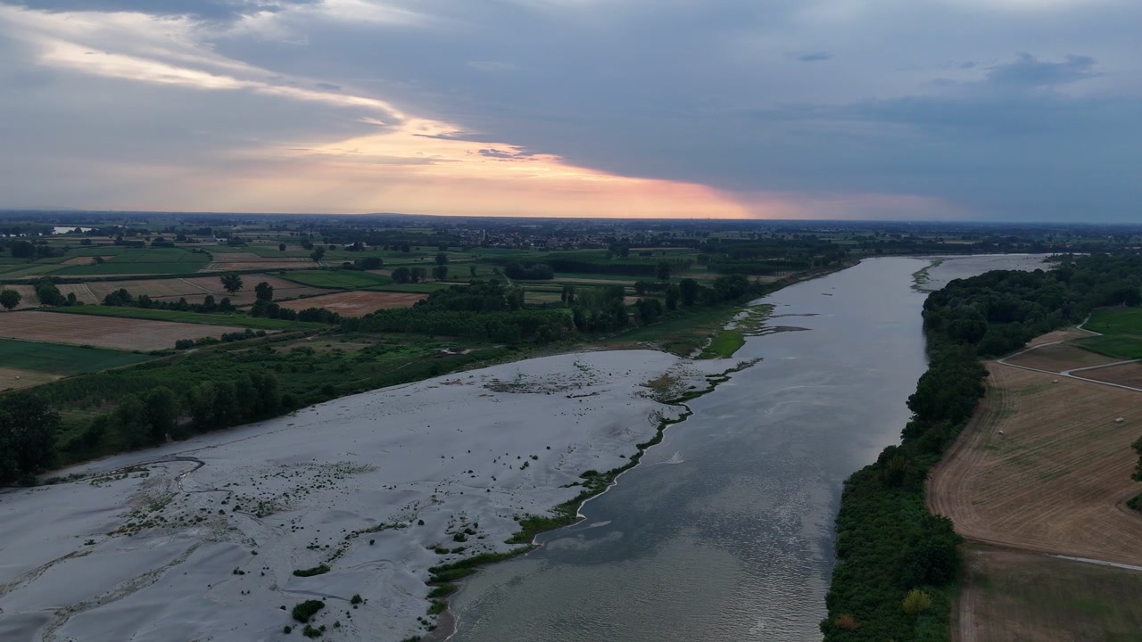 Il fiume Po mostra sedimenti esposti e un flusso d'acqua ridotto vicino a Isola Serafini, Monticelli d'Ongina, Piacenza, Emilia-Romagna, Italia, Europa meridionale, sorvolo in avanti con drone.