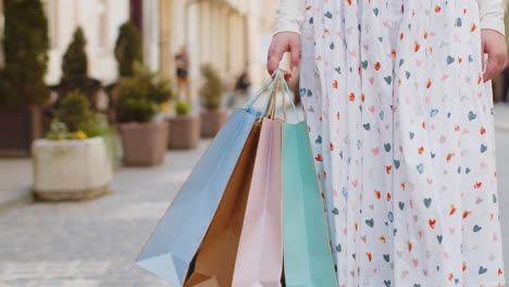 anonymous woman shopaholic consumer after shopping sale with colorful bags with gifts outdoors city