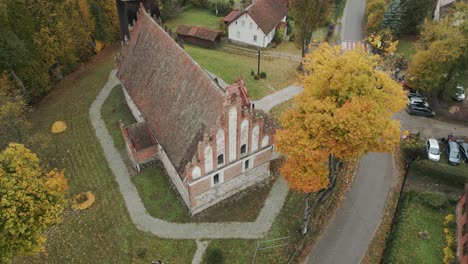 Antigua-E-Histórica-Iglesia-Con-Una-Torre-De-Madera,-Colores-De-Finales-De-Otoño-En-El-Campo