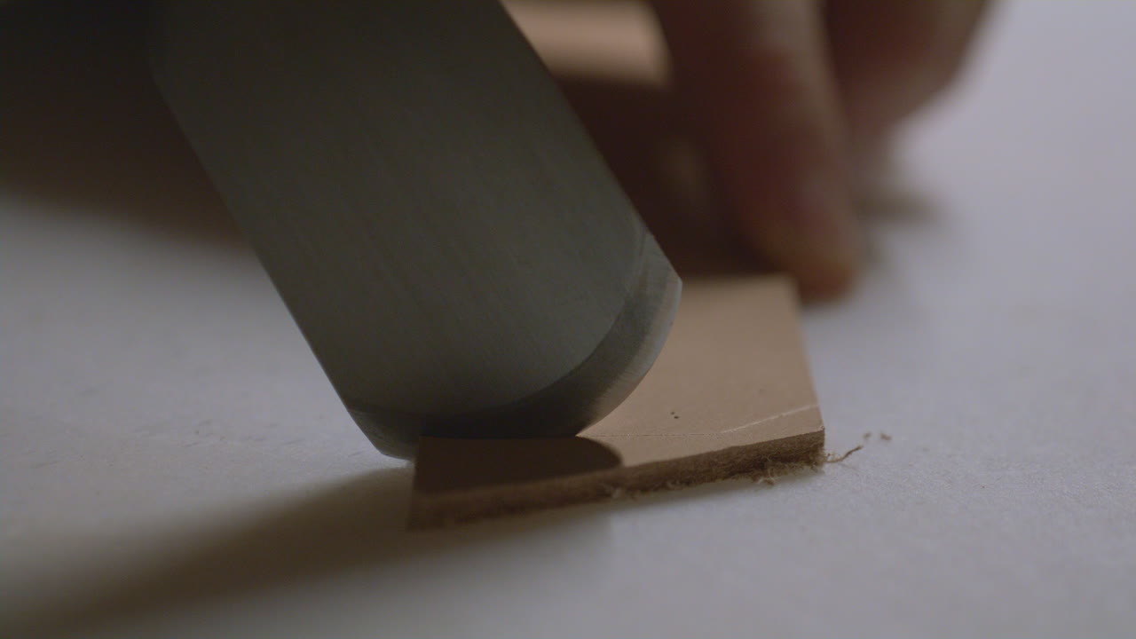 A detailed macro shot of a sharp chisel precisely cutting through a piece of thick leather.