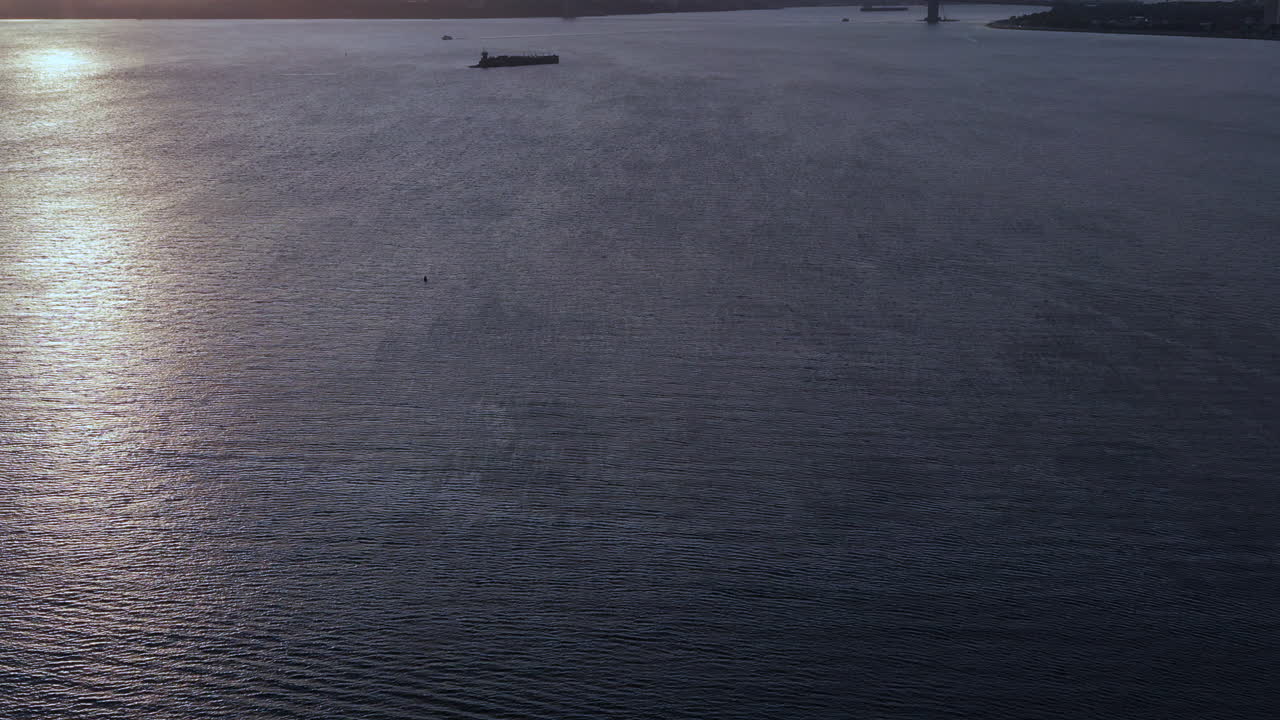 a dramatic pan up as the drone camera rises to bring into view a golden sunset and The Verrazano Bridge in Brooklyn, New York