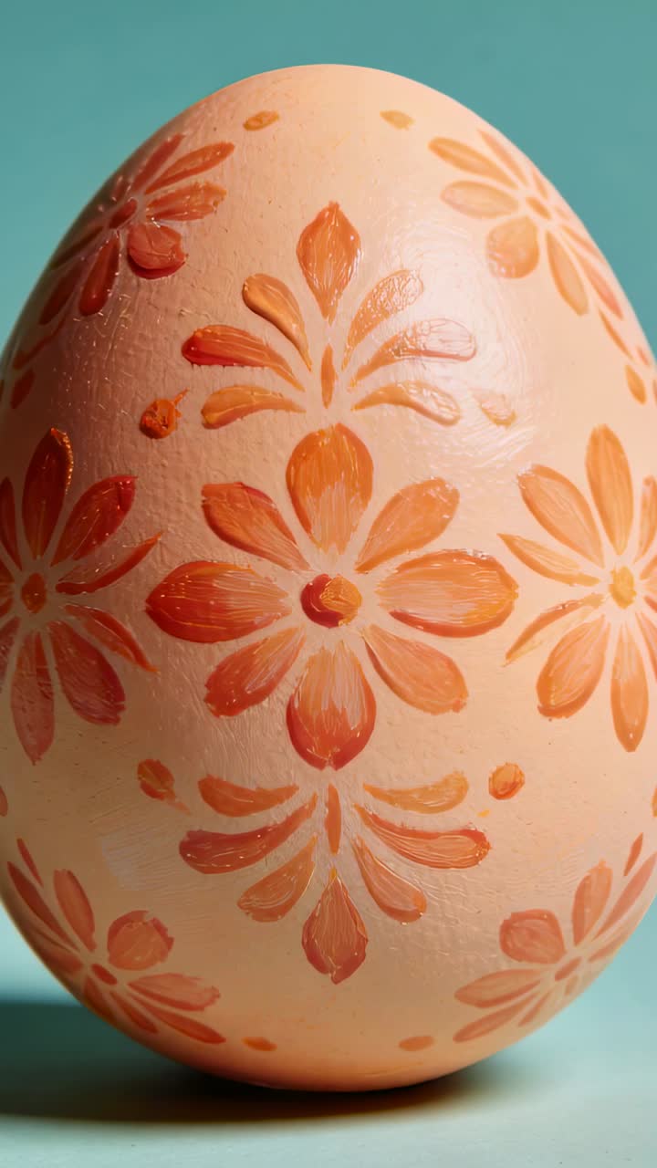 Vertical video: Shifting camera showing painted egg rotating slightly on teal backdrop with gloss