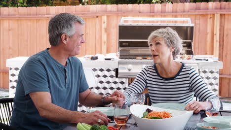 senior white couple talking together at lunch in the garden