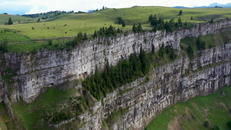 Revealing-drone-shot-of-Creux-du-Van-in-Switzerland,-located-at-the-border-of-the-cantons-of-Neuenburg-and-Vaud