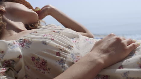 Mujer-Tranquila-Durmiendo-Una-Siesta-En-La-Playa-Cubriendo-La-Cabeza-Con-Un-Sombrero-De-Cerca.-Niña-Acostada-Costa