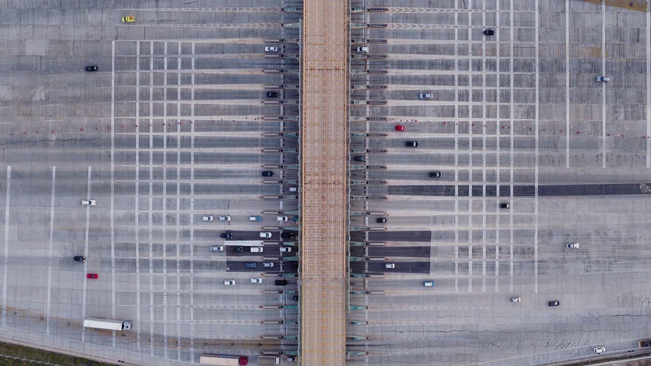 Top-down drone shot of a toll station. Cars crossing highway booths directly below. Aerial overhead infrastructure stock footage