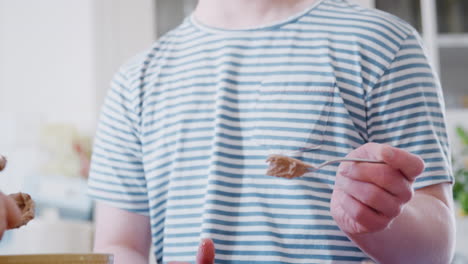 young downs syndrome couple decorating homemade cupcakes with icing in kitchen at home