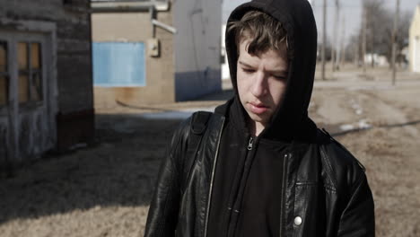 a young high school aged teen boy wearing a backpack walking down a road during the winter on a cold day-1