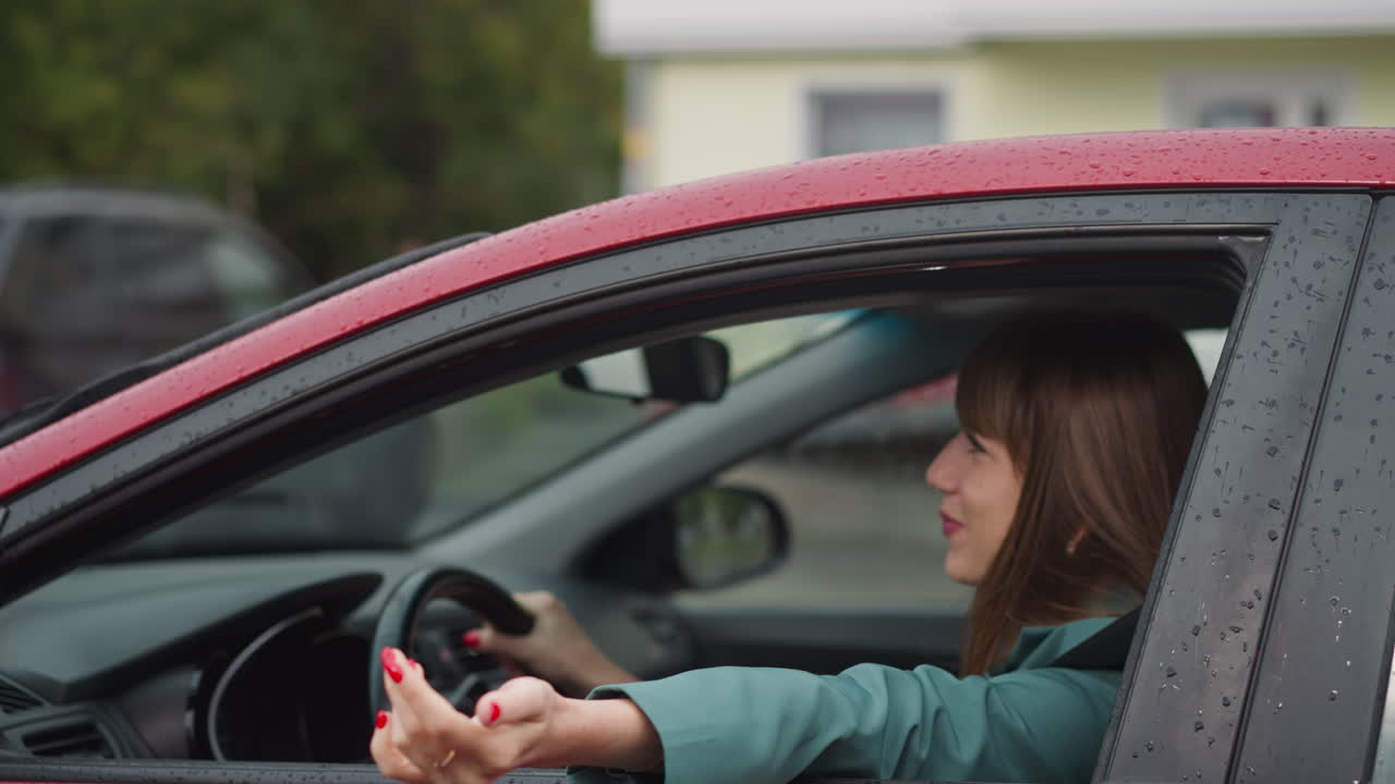 Mulher encantada dirige carro, esticando a mão para fora da janela.