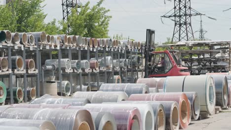 forklift driver loads rolls of steel sheet. industrial warehouse with rolls of steel sheet