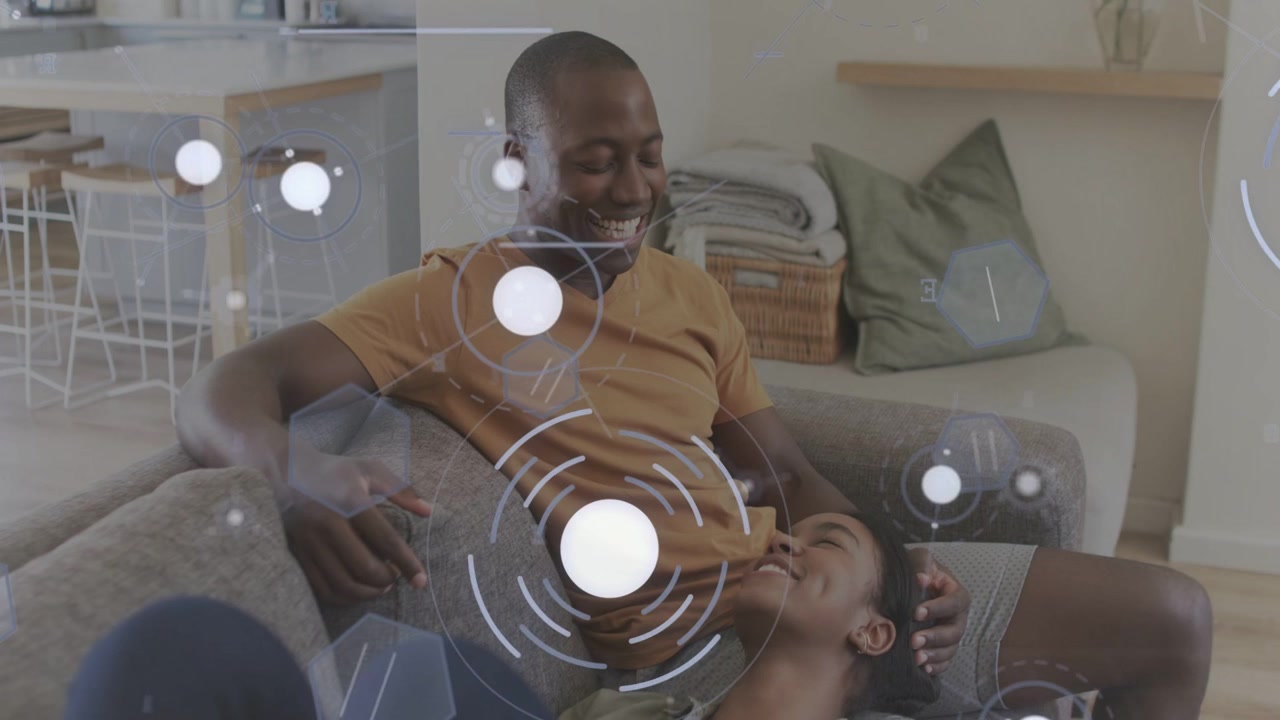 Couple sitting on couch, man looking down and cradling head while HUD graphics supporting wellness