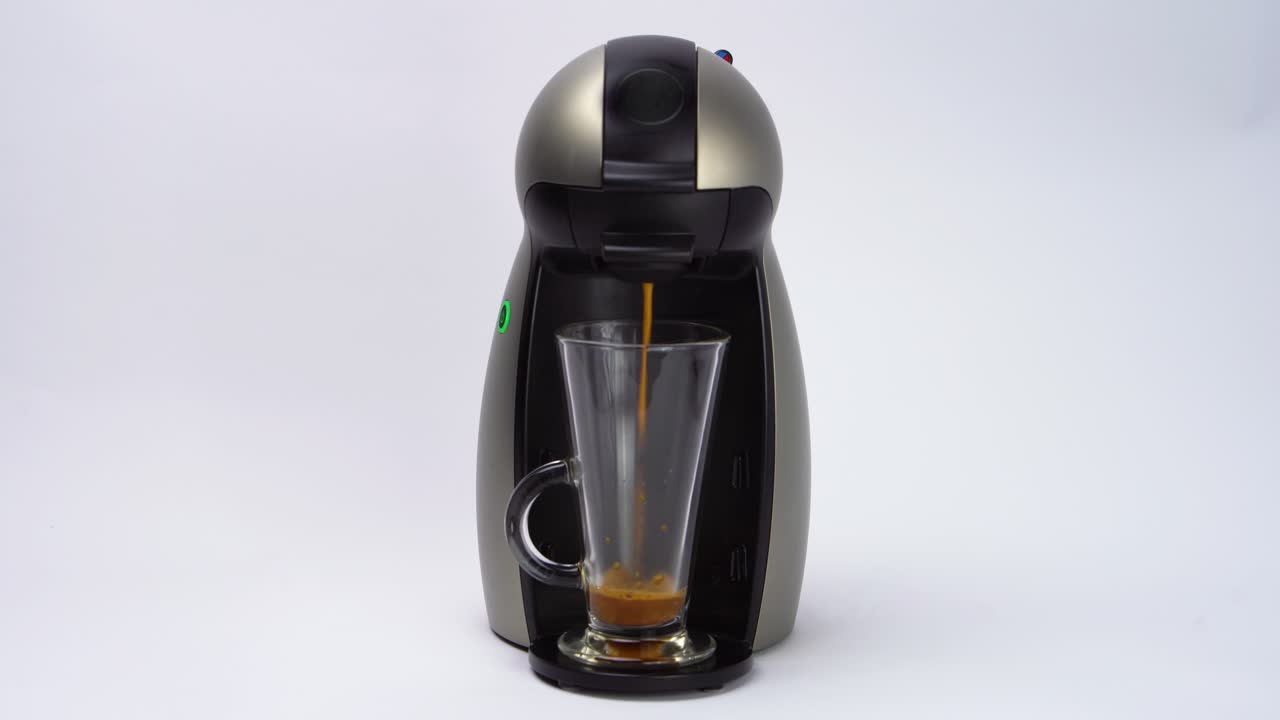 máquina aislada que vierte café cremoso caliente en una taza de vidrio vacía sobre fondo blanco