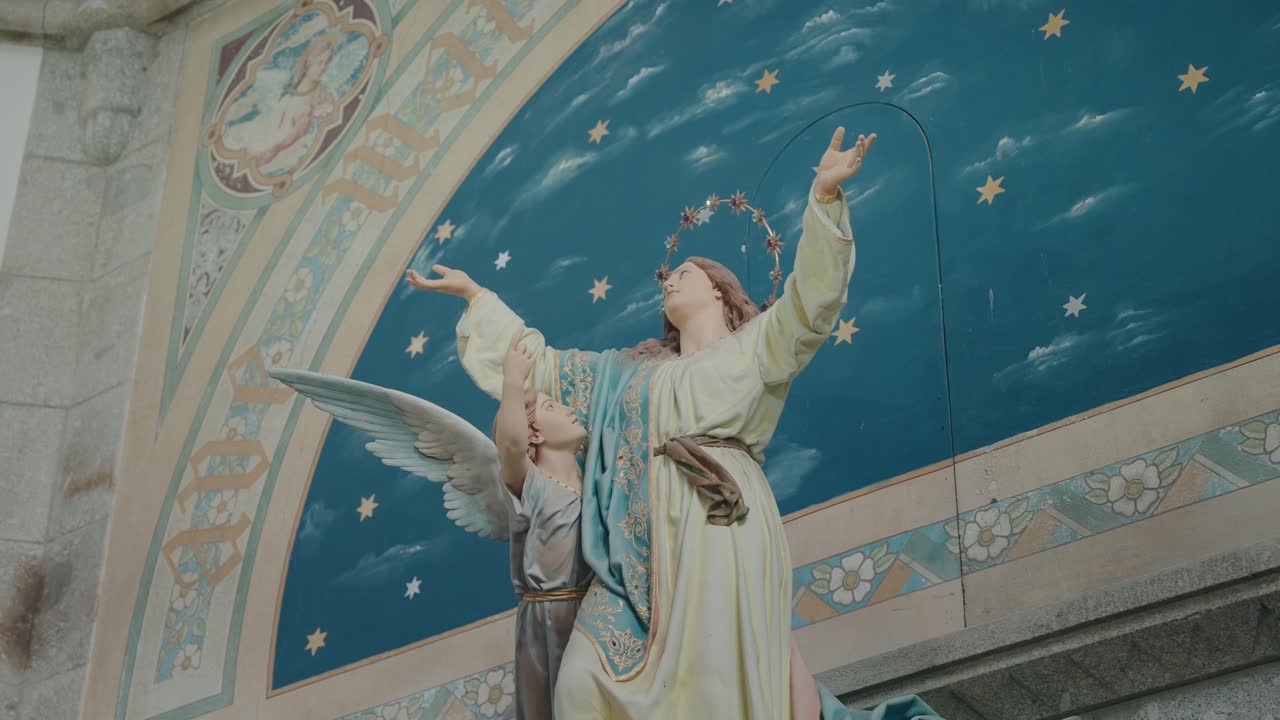 Detailed statue of Virgin Mary and angel with painted blue starry sky on church wall