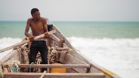 african teenage fisherman rowing canoe at sea