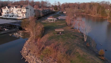 aerial drone footage flying out from a point of land over a lake with nice houses and boat docks at sunset