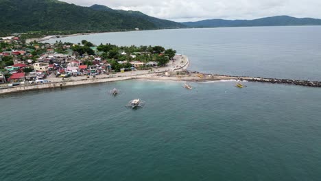 vista aérea de impresionantes aguas turquesas del océano con simples botes bangka flotando en la costa de una comunidad pesquera de una isla rural