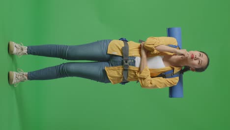 full body of asian female hiker with mountaineering backpack thinking about something and looking around while standing on green screen background in the studio