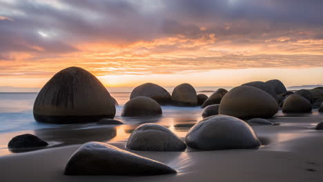 long exposure of smooth boulders on a beach at sunset