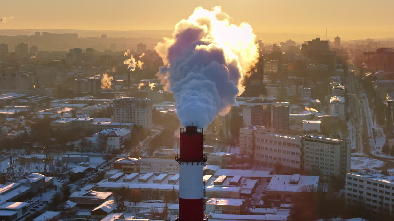 Aerial drone view of a working thermal power station in Chisinau city covered in snow at sunset. Steam and smoke coming from pipes. Moldova