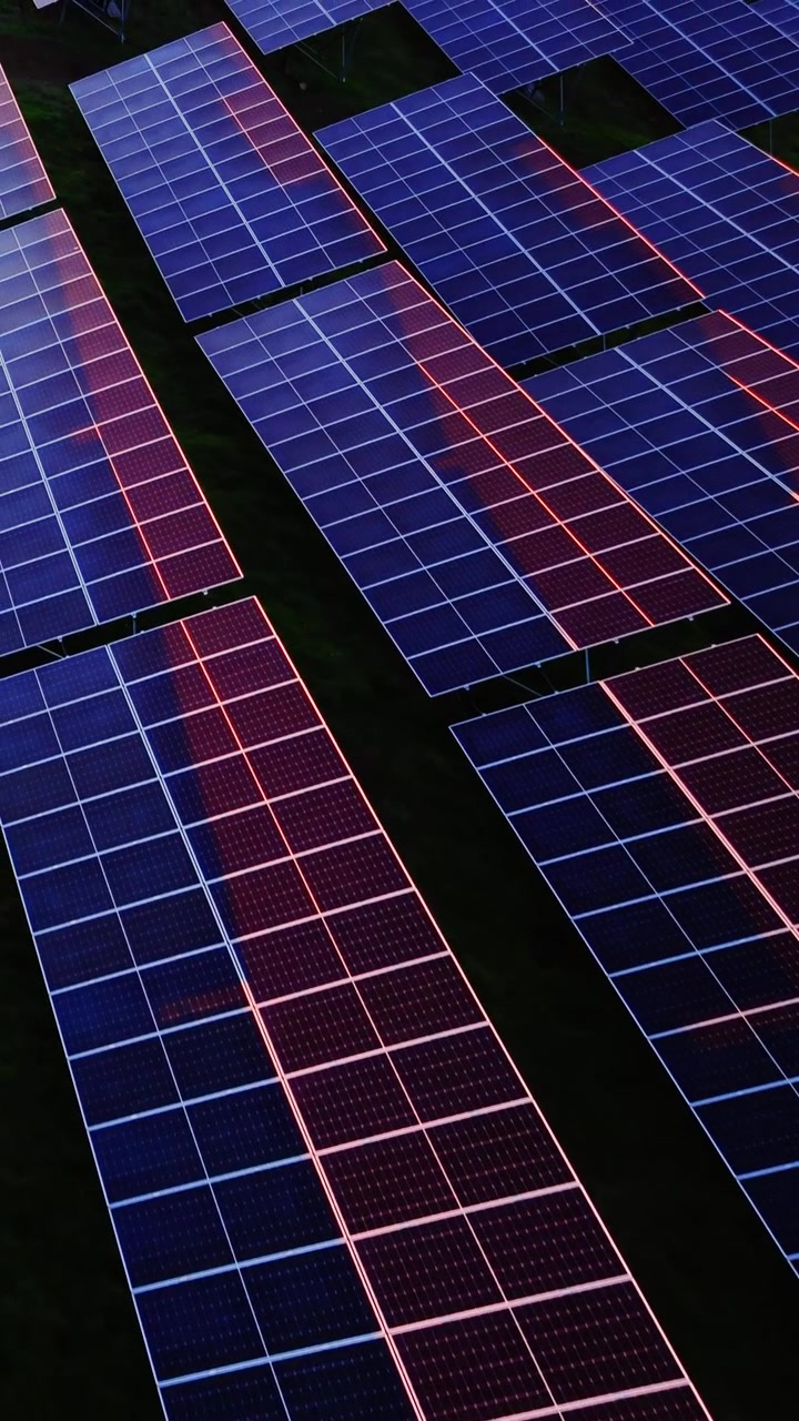 Motivo di moduli di pannelli solari. Prospettiva dall'alto della texture di una griglia fotovoltaica, toni blu e illuminazione al tramonto. Video verticale