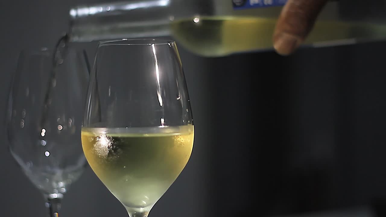 Vino bianco versato in un bicchiere su un tavolo con sfondo nero, senza persone, video stock, filmato stock