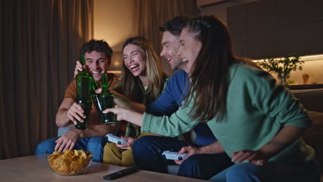 happy friends clinking beer bottles at home gathering late evening close up.