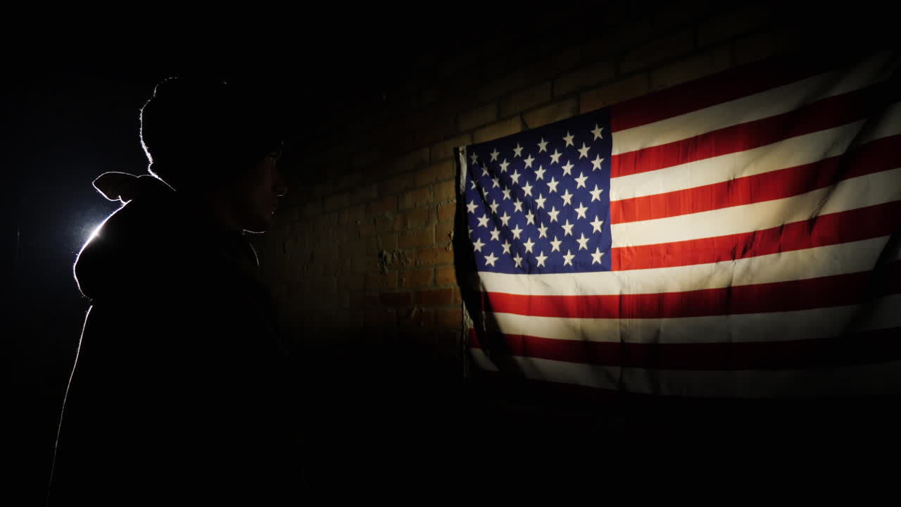 un joven soldado en el centro de atención mira la bandera estadounidense