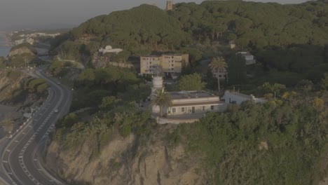 Aproaching-to-Calella-little-lighthouse-while-rising-above-it,-located-in-Calella,-Catalunya,-Spain,-shoted-in-Dlog