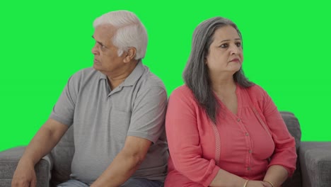 una pareja de ancianos indios enojados sentados de espaldas a espaldas en la pantalla verde