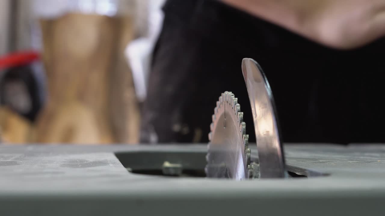Hands removing and inspecting a table saw plate and blade indoors