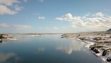 Cinematic-drone-shot-over-the-Olfusa-river-near-Selfoss-Iceland-with-sky-reflecting-on-the-water