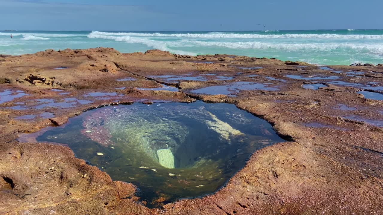 Stunning view looking over the rocks and crystal clear rock pools towards the gorgeous turquiose tropical ocean on Queensland's holiday hotspot, North Stradbroke Island