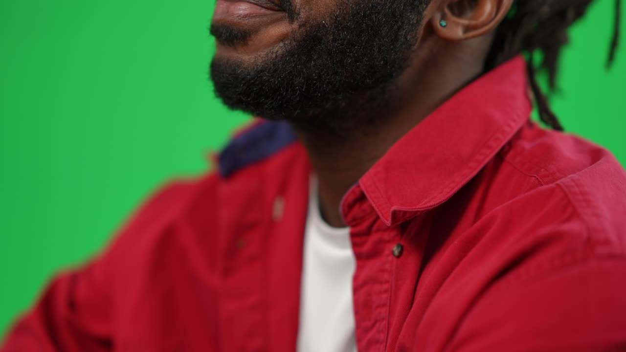 Close-up unrecognizable bearded African American man talking watching football match on green screen. Concentrated sport fan cheering supporting team on championship match. Chromakey background.