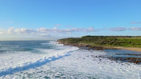 small rocks at the sandy waterfront and green landscape of maroubra in sydney, australia