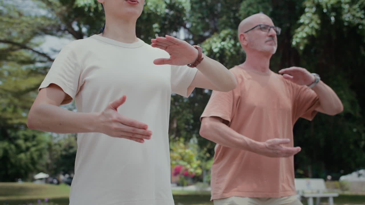 Mature Sportsmen Doing Circular Moves with Arms in Park
