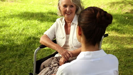 nurse talking to woman in wheelchair outside